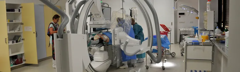Angiografie v nemocničním sále s lékařem provádějícím vyšetření.