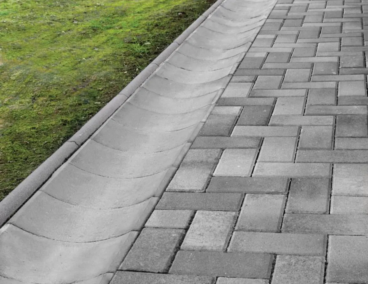 Instalovaný betonový žlab vedle dlažby pro odvodnění.