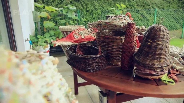 Ručně pletené košíky a předměty z recyklovaných materiálů na venkovním stole.