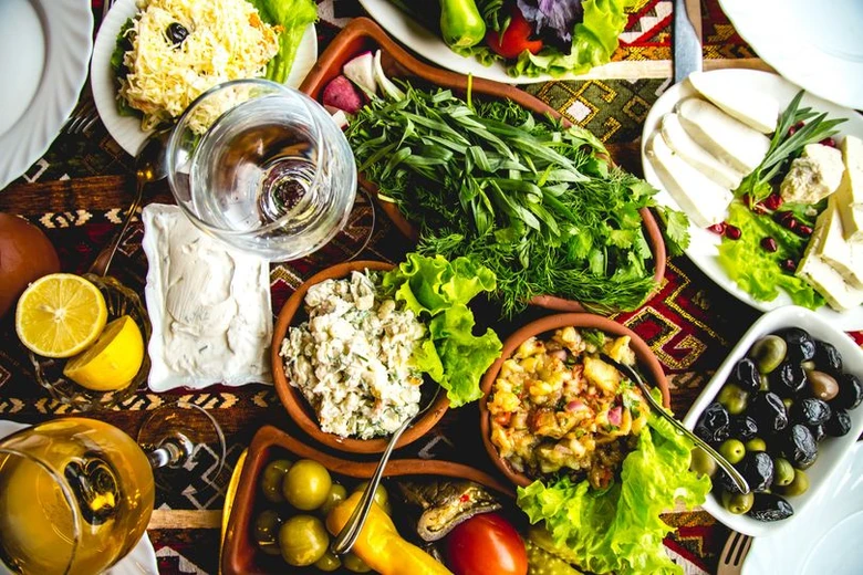Středomořská dieta: sýr, olivey, zelenina a víno na stole.