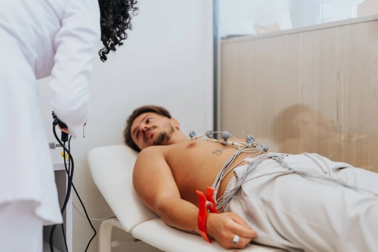 Muž leží na stole s elektrodami pro EKG při preventivní prohlídce.