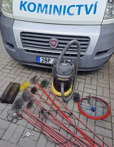 Nástroje pro revizi komína ležící před vozem s nápisem KOMINICTVÍ.