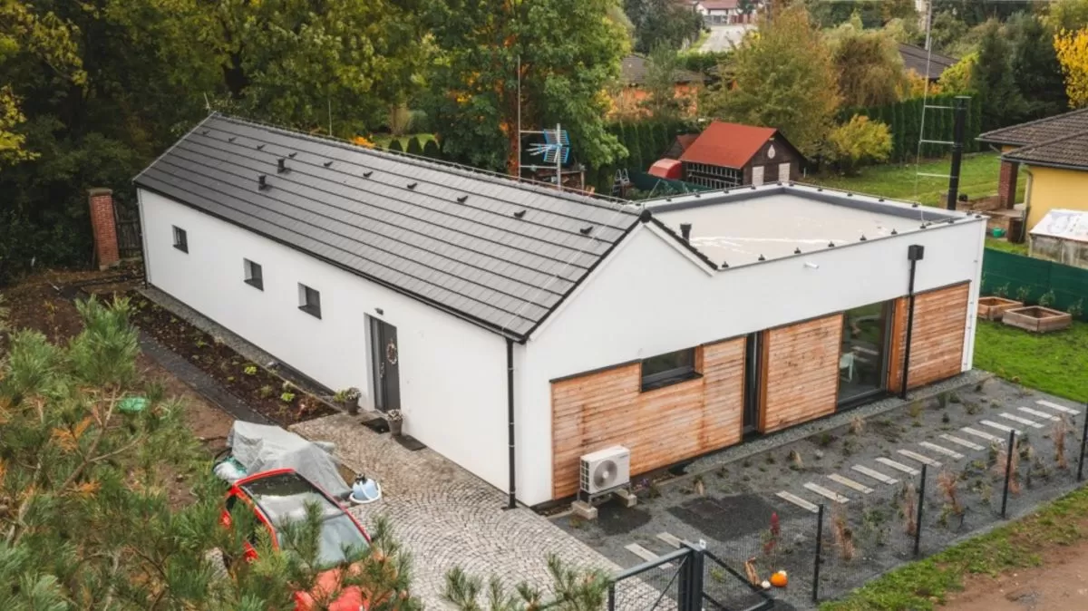 Moderní rodinný dům s dřevěnými prvky na pozadí zelené zahrady.