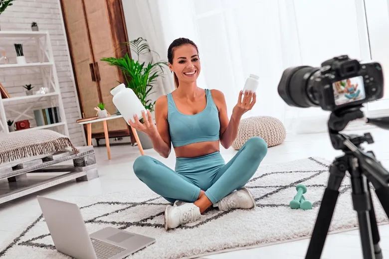 Žena v sportovním oblečení natáčí video s doplňky stravy pro sociální síť.
