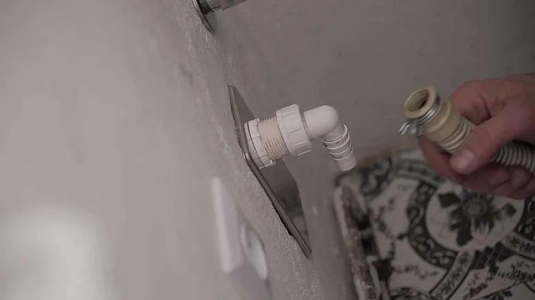 Ručník připojuje hadici odvodní pračky k plastovému výpustnému ventilu.