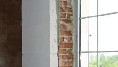 Okno s odhalenou cihlovou zdí během přípravy na vnitřní zateplení.