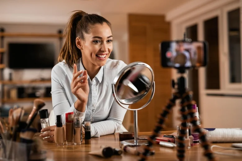 Žena natáčí tutorial na make-up s kosmetikou před sebou.
