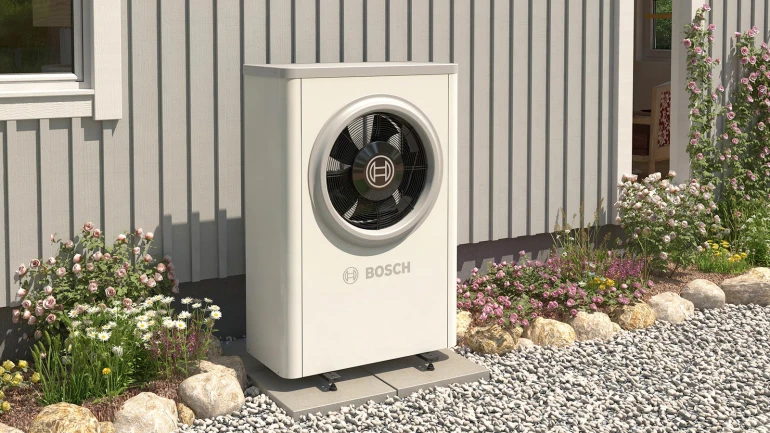 Bosch tepelné čerpadlo venku u domu s květinami.