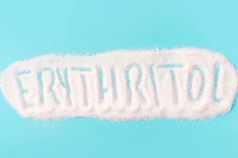 Bílý prášek s nápisem erythritol na modrém pozadí.