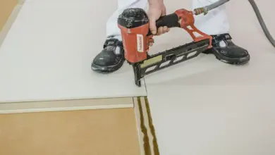 Montáž suché podlahy pomocí kladiva na hřebíky.