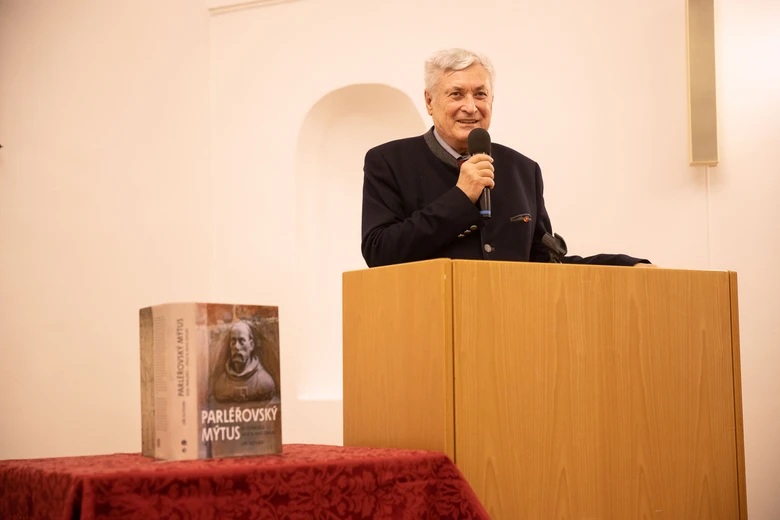Man speaking at podium with book