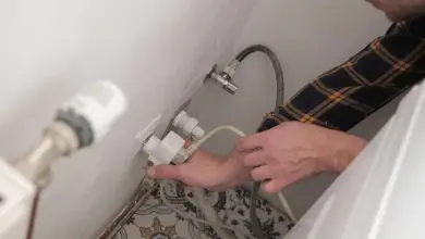 Ruční připojení vodovodních hadic k pračce během instalace.