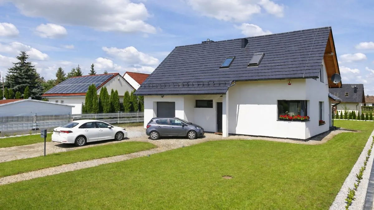 Moderní rodinný dům s fotovoltaikou, dvěma auty na dvorku.